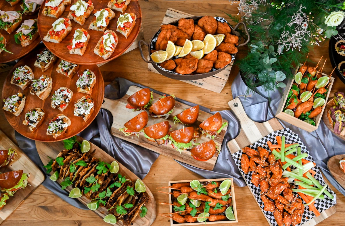 Pohled shora na cateringový stůl s bruschettami, burgery a taci
