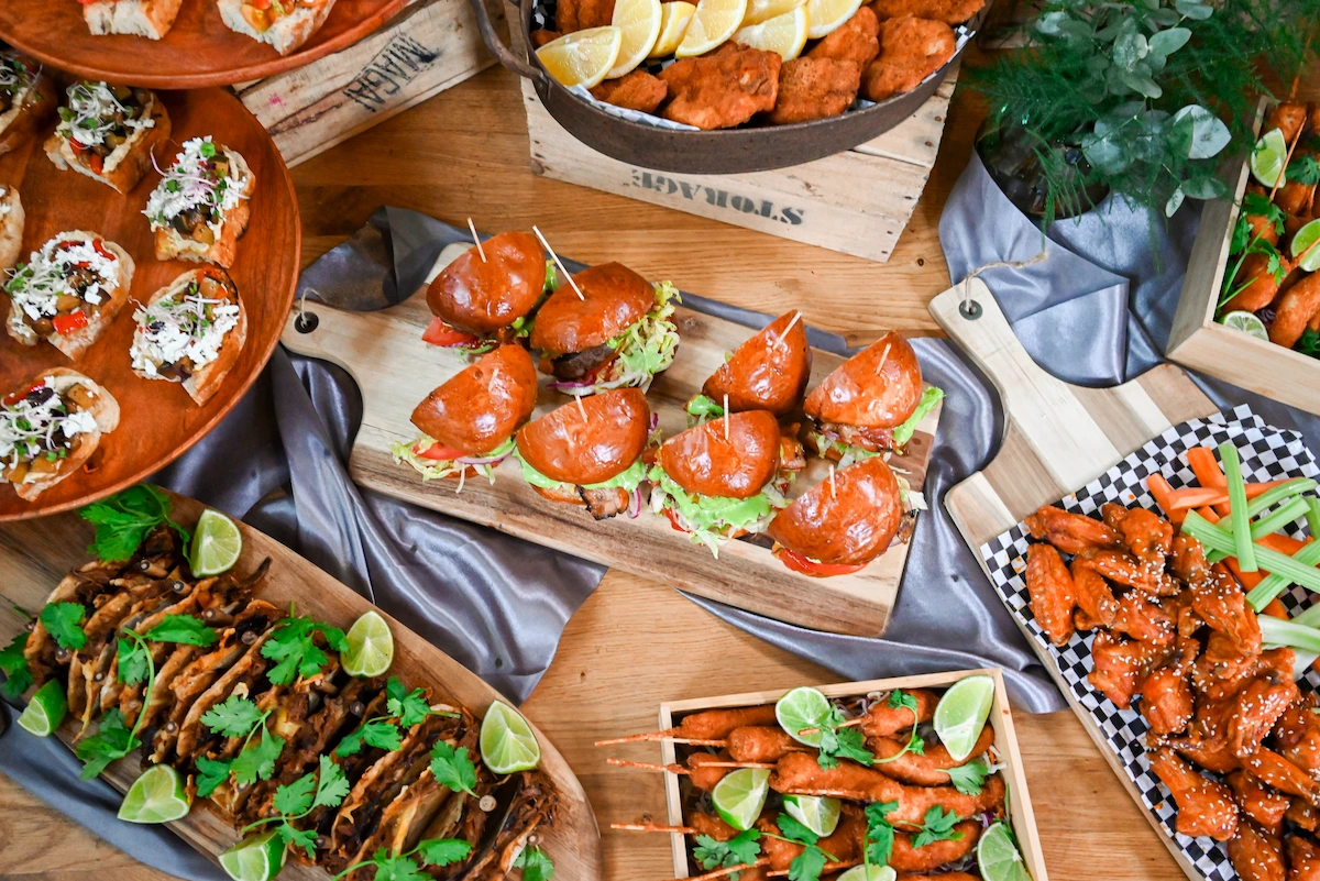 Mini burgery, tacos a kuřecí křídla na dřevěném prkénku